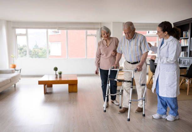 senior man trying to walk with a walker and with the assistance of his doctor and his wife - latin american and hispanic ethnicity senior adult mature adult couple imagens e fotografias de stock