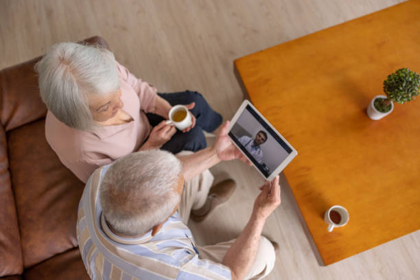 Senior couple at home talking to a doctor on a video call Latin American senior couple at home talking to a doctor on a video call - telemedicine concepts hospice stock pictures, royalty-free photos & images
