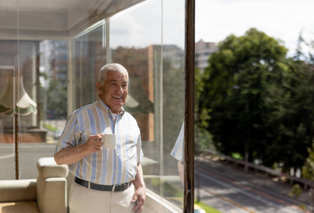 istock Happy senior man drinking a cup of coffee while looking at the view through the window 1395652002
