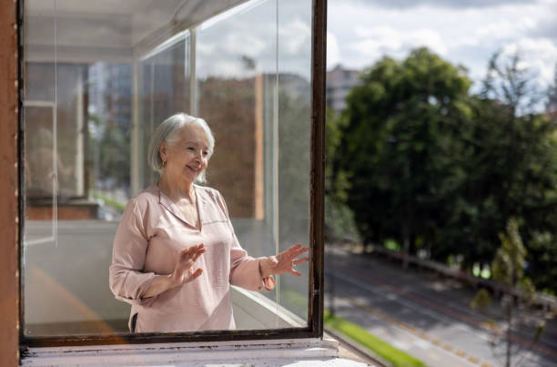 istock Senior woman at home looking at the view through the window 1395652021