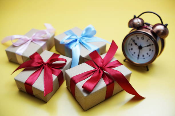 istock Gift boxes and alarm clock on yellow background 1395652148