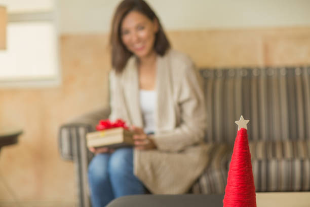 Asian woman sitting on the sofa holding a gift.