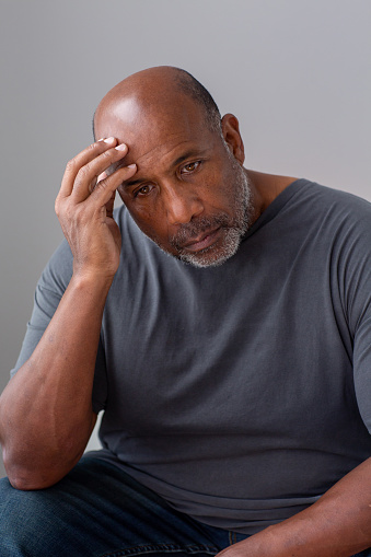 Mature African American man not feeling well with his hands on his head.