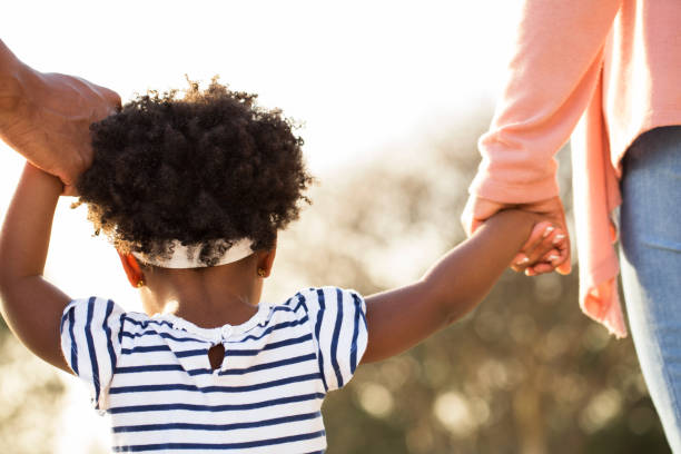 istock Little girl holding hands with her parents. 1395654321