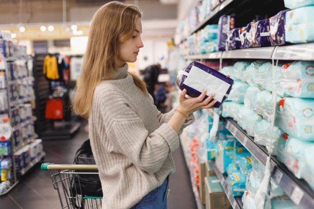 若い女性の母親は、ショップモールのスーパーマーケットでおむつを選びます。 - diaper shopping human pregnancy supermarket ストックフォトと画像