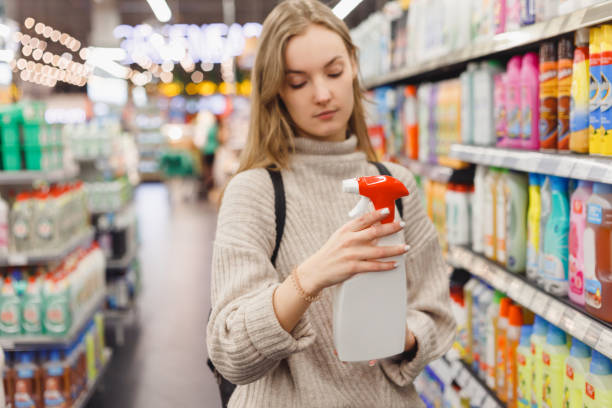 istock Young woman choosing spray for kitchen, bathroom at store 1395656890