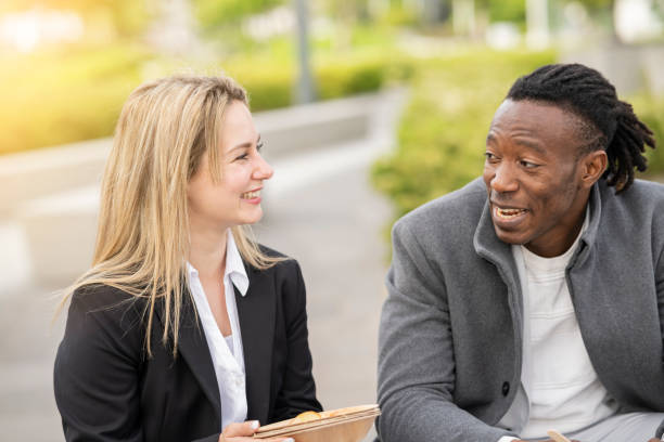 istock multiracial coworkers talking outdoors while having lunch - business people concept - 1395660657