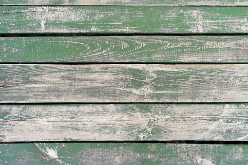 Wooden background. Old green painted wooden plank surface, aged weathered cracked boards. Grunge shabby texture.