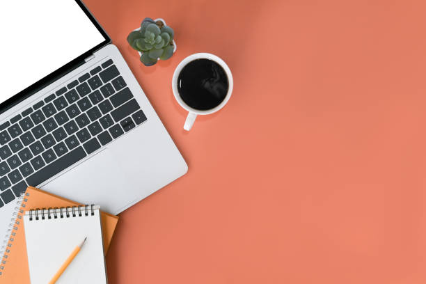 istock Computer laptop, notepad and coffee cup on orange background. Flat lay, Top view with copy space. 1395669281