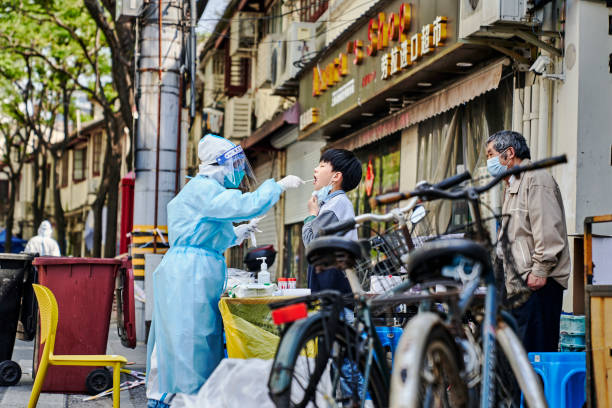 a medical worker wearing protective gear conducts  nucleic acid testing on residents in shangai's lockdown - china covid imagens e fotografias de stock