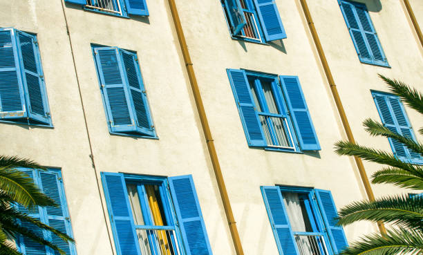 istock Closed and open blue shutters on windows at building 1395672810