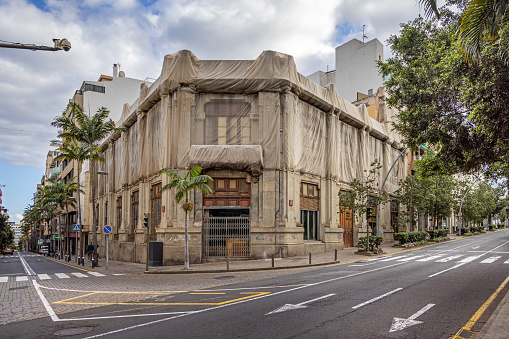 Old Spanish building wrapped in tarpaulin to prevent stones to fall down in the street in the center of Santa Cruz which is the main city on the Spanish Canary Island Tenerife