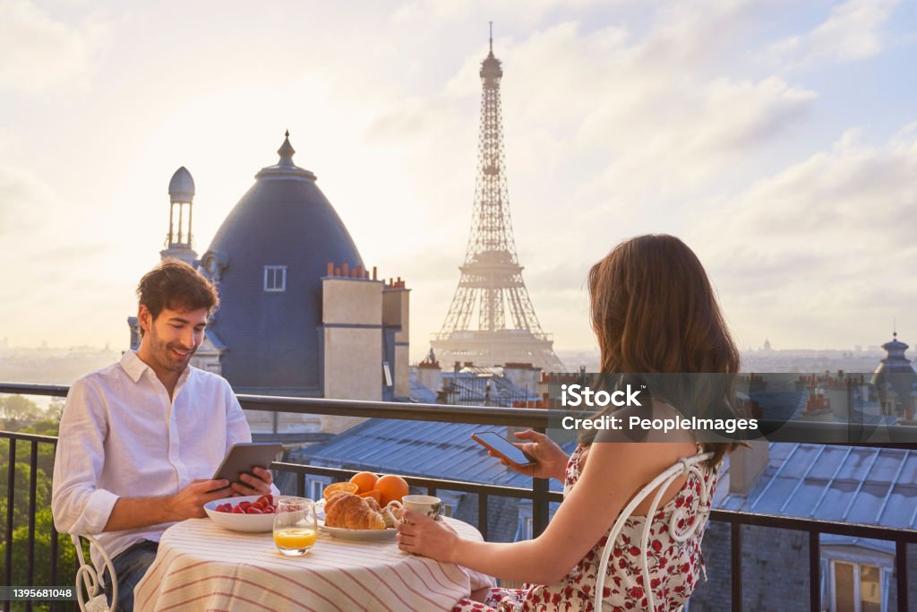 Shot of a young couple having breakfast on the balcony of an apartment overlooking The Eiffel Tower in Paris, France Nothing says honeymoon like a trip to Paris Paris - France Stock Photo