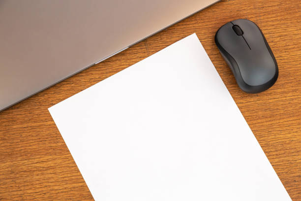 istock Minimal wooden work desktop with blank page with copy space, laptop, mouse. Top view, text space, mock up. Office desk. 1395681061