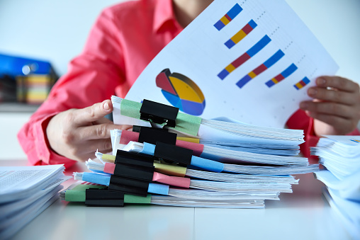 Accountant woman hands holding stacks files, business reports and stock charts. Financial and paperwork concept