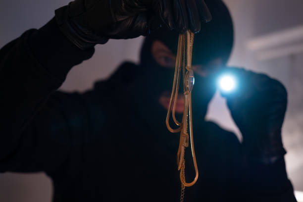 Thief with black mask breaking and entering into the apartment.