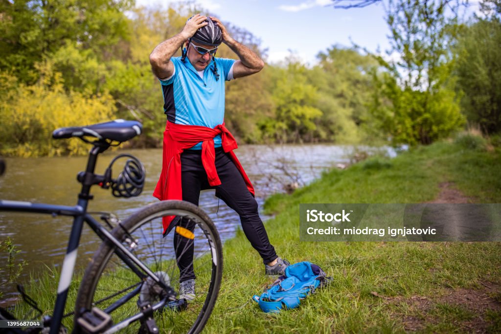 Active senior man adjusting hic cycling helmet Active and healthy senior man, preparing himself for a bike ride in the nature 65-69 Years Stock Photo