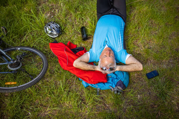 Active and healthy senior man, lying on the grass while taking break from bike ride