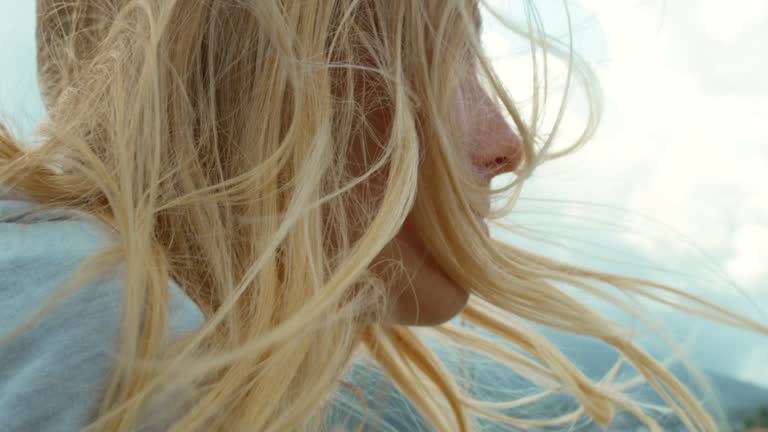 Closeup of a blonde woman with her hair blowing in her face on a windy day on a yacht. Young woman with her hair blowing in the wind around her face during a cruise