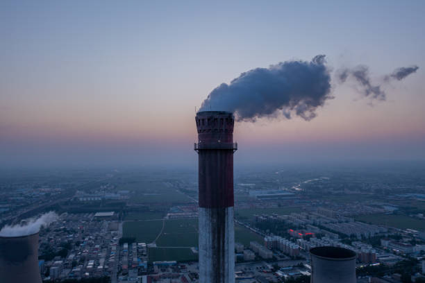 vista aerea dei tubi alti della centrale elettrica a carbone con fumo nero che si muove verso l'alto dell'atmosfera inquinante all'alba - vista verso lalto foto e immagini stock