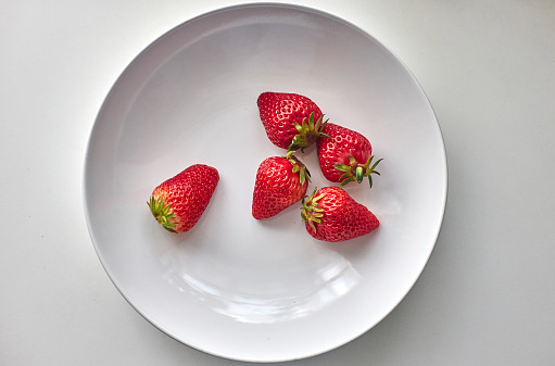 fresh strawberries in white plate, directly above