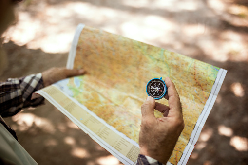 Senior hiker looking at hiking map and compass