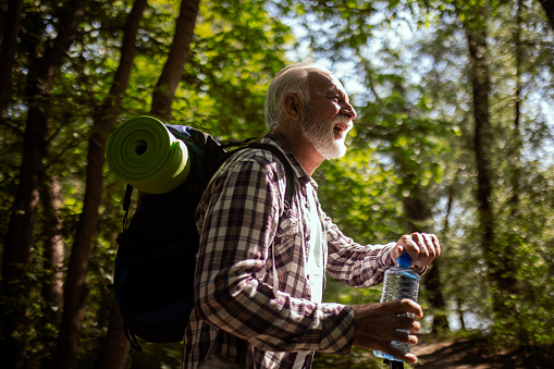 Senior man hiking ,taking a break hydrating