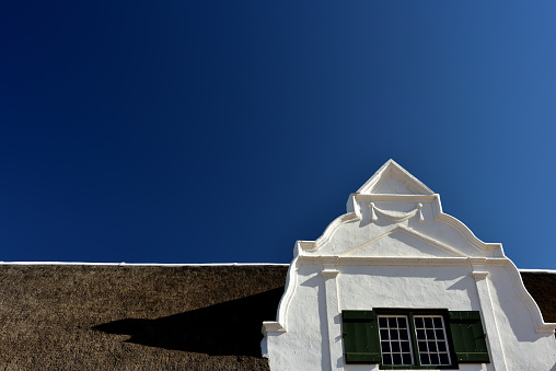 A great example of a well-kept Cape Dutch gable and thatch roof against a bright blue sky