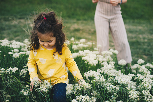 A woman and her three year old daughter smile while they play outdoors in the springtime.