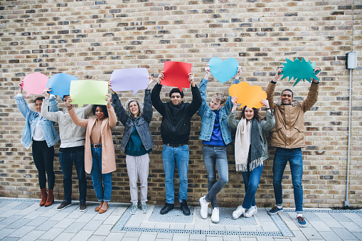 Young adult friends holding up copy space placard thought bubbles