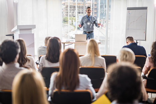 Happy mid adult leader talking to his colleagues during a business presentation in a board room.