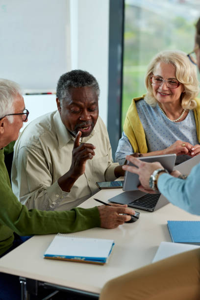 istock Young hipster educator teaching group of senior multiracial people using technology and the internet in the classroom. 1395693290