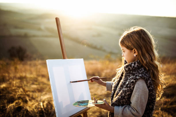 Little girl enjoying while painting in autumn day outdoors.