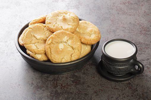 White Chocolate Caramel soft and macadamia nuts baked cookies served with cup of milk on the table close-up. Horizontal