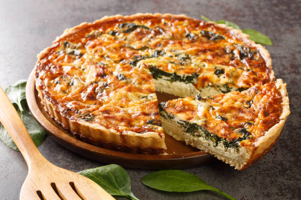 istock Quiche Florentine with spinach, cheese, eggs and spices on table with spatula, close-up. Hotizontal 1395693709