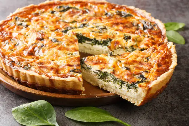 Photo of Quiche Florentine is a fresh spinach quiche baked in a homemade pie crust to serve for brunch or breakfast for dinner close-up. Hotizontal