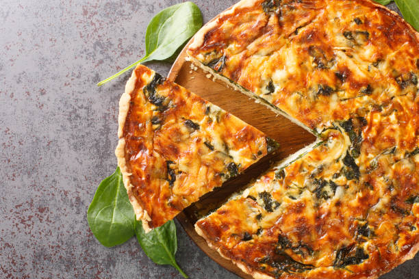 istock Quiche Florentine with spinach, cheese, eggs and spices on table with spatula, close-up. Hotizontal top view 1395693824