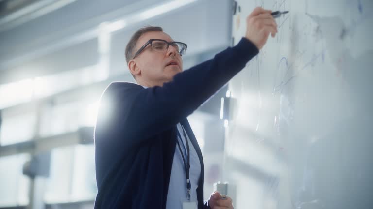 Teacher Talk to Students and Use Chalkboard at University Lecture Class. Smart man Draw Formulas and Schemes at Seminar. Genius Solves Problems Concept