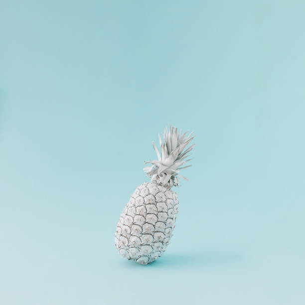 istock Pineapple colored in white balancing on blue background. Minimal summer concept. 1395696250
