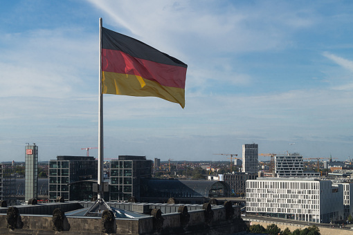 Skyline of Berlin on a clear sunny midday with the german flag swinging in the wind.