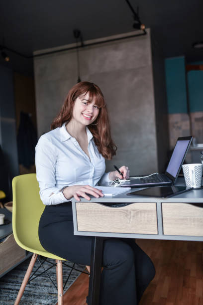 istock Cute Female Redhead Smiling While Working From Home 1395697132