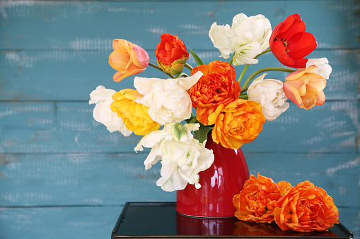 bouquet of red tulips in a vase on a wooden background