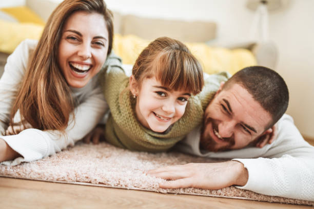 istock Cute Family Smiling And Relaxing While Laying Embraced On Carpet 1395697779