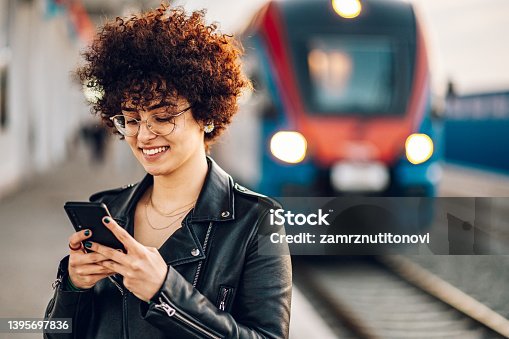 istock Woman waiting on a train station platform and using smartphone 1395697836