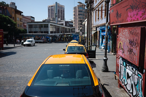 Valparaiso, Chile - February, 2020: Taxi with yellow roofs parked in row along Avenida Ecuador street in Bellavista district. Row of city taxis parked in parallel waiting for customers in Valparaiso