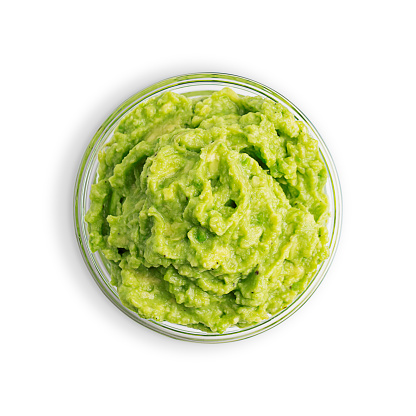 Top view of traditional mexican dip, sauce, spread or salad made of mashed ripe green avocado served in glass bowl as snack or appetizer for vegan or vegetarian dieting cut out on white background