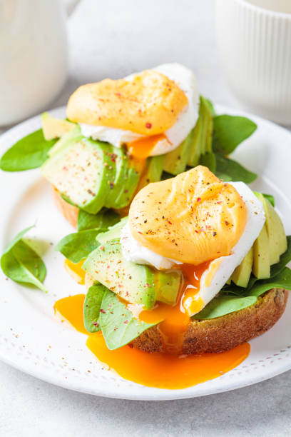 istock Eggs benedict on bun with spinach, avocado and hollandaise sauce. Delicious vegetarian breakfast concept. 1395698829