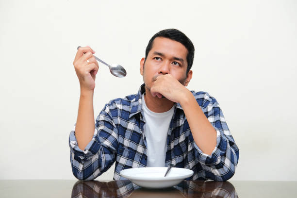istock Adult Asian man sitting in front of empty plate while showing confused expression 1395698956