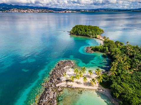 Aerial view of tropical island surrounded by pristine blue water and coral reef in Tonga