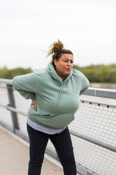istock Obese Hispanic woman with back pain amid workout 1395704658
